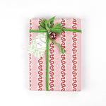 red and pink striped wrapping paper in fancy stripe patterns wrapped in a green velvet ribbon and a gift tag with ball ornament