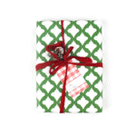 Front view of gift wrapped in green and white patterned paper with red ribbon and plaid gift tag.