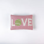 A pink pillow with the word "LOVE," where the "O" is a green tennis ball
