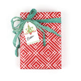 Front view of wrapped gift in red geometric paper with green ribbon and Christmas tree gift tag.