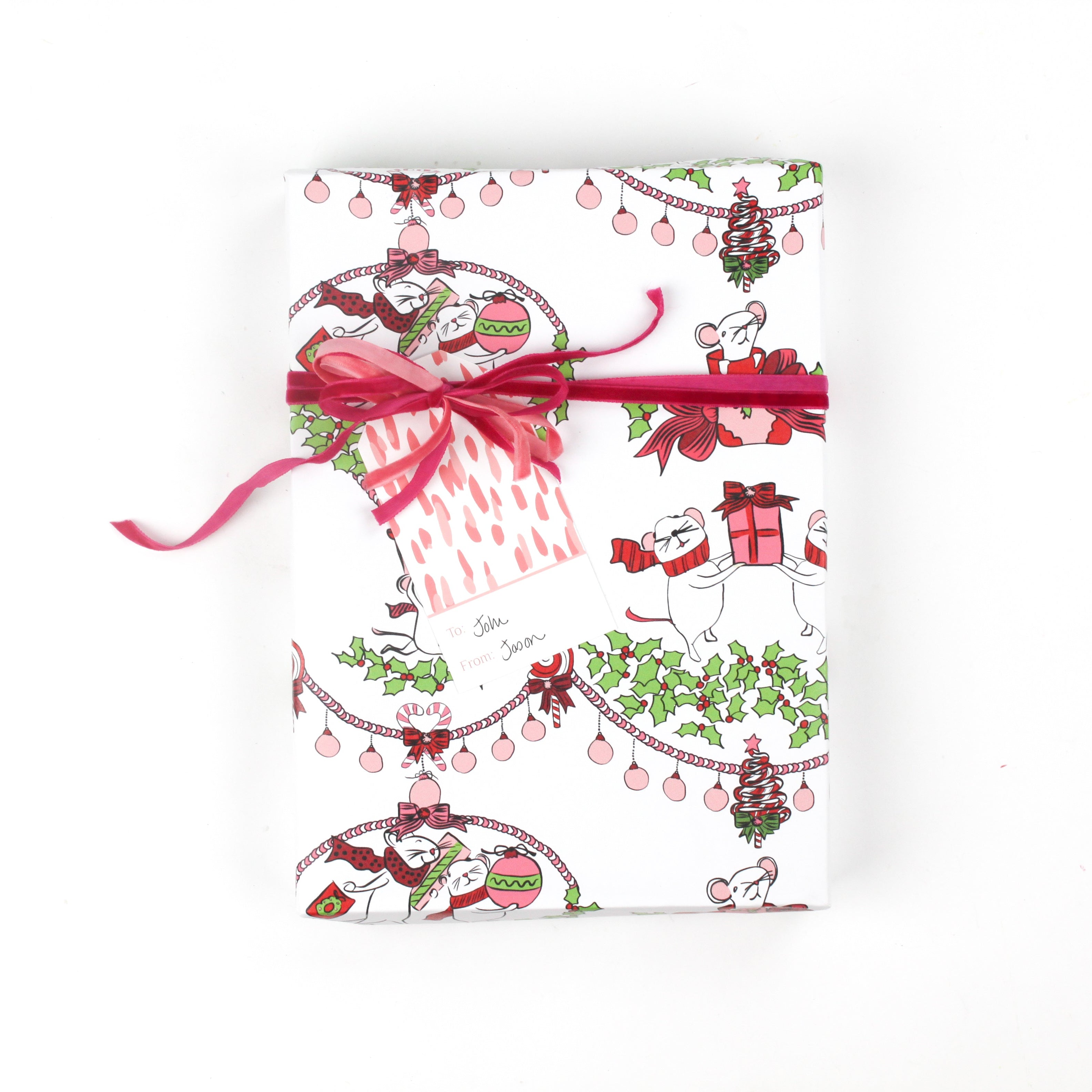 Front view of gift wrapped in mouse-themed holiday wrapping paper with pink ribbon and gift tag.