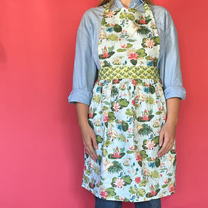 a woman wearing a green, pink and blue floral apron featuring the Meadow bluc water lilies pattern fabric from madcap cottage