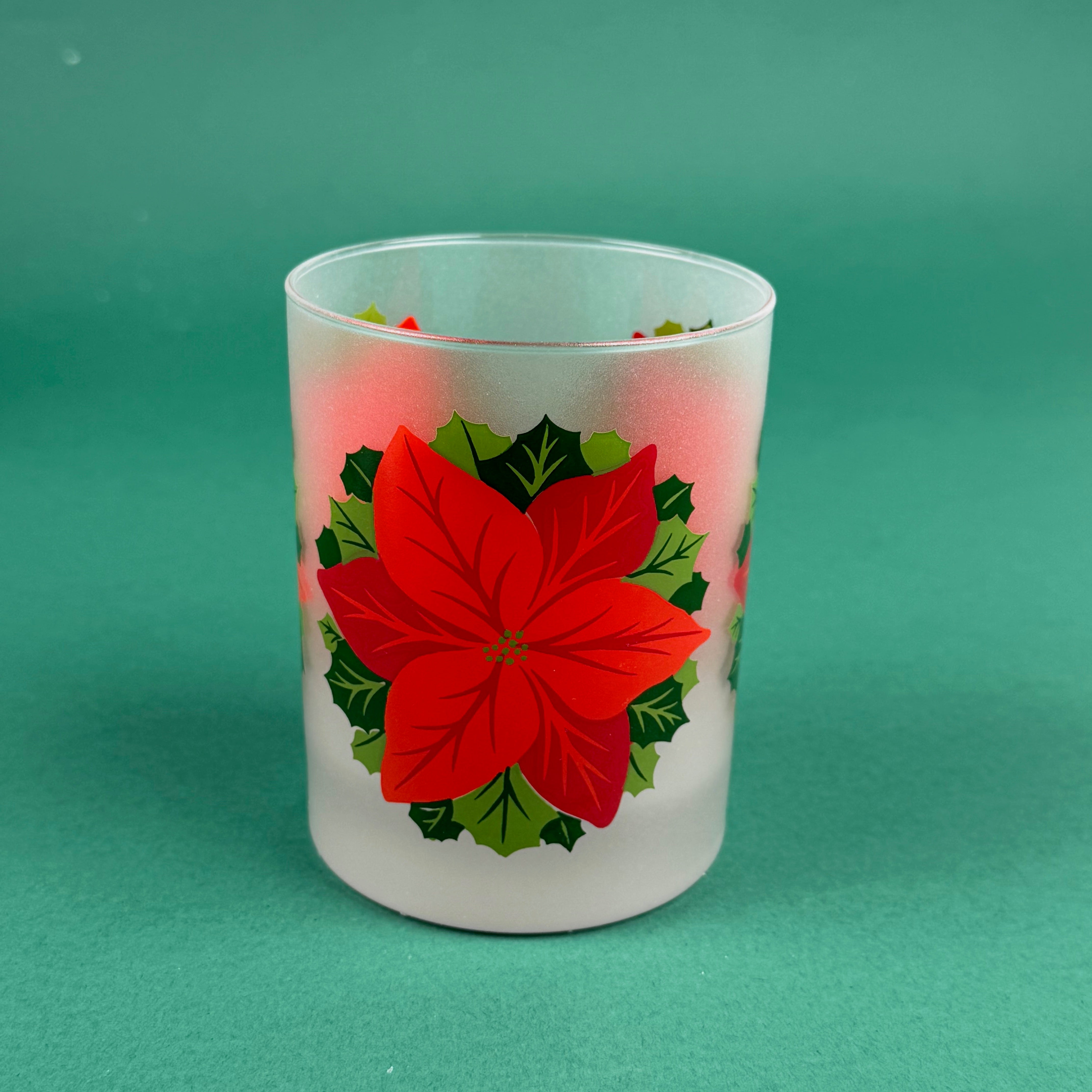 Frosted clear glass with a bright red poinsettia and green holly leaf design on a green background