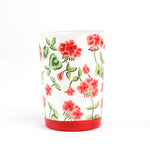 a Hand-painted glass with red geraniums and a red band around the base in a white background