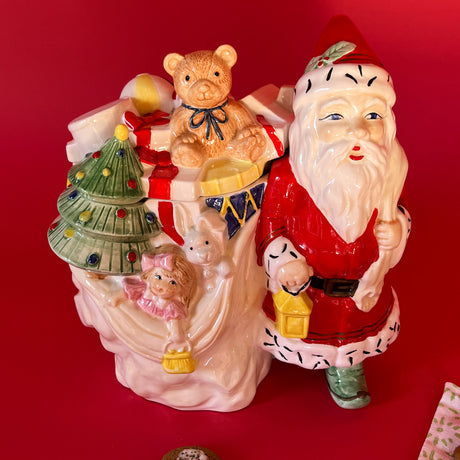 a vintage ceramic santa cookie jar with santa holding a sack full of toys and holding a yellow lantern
