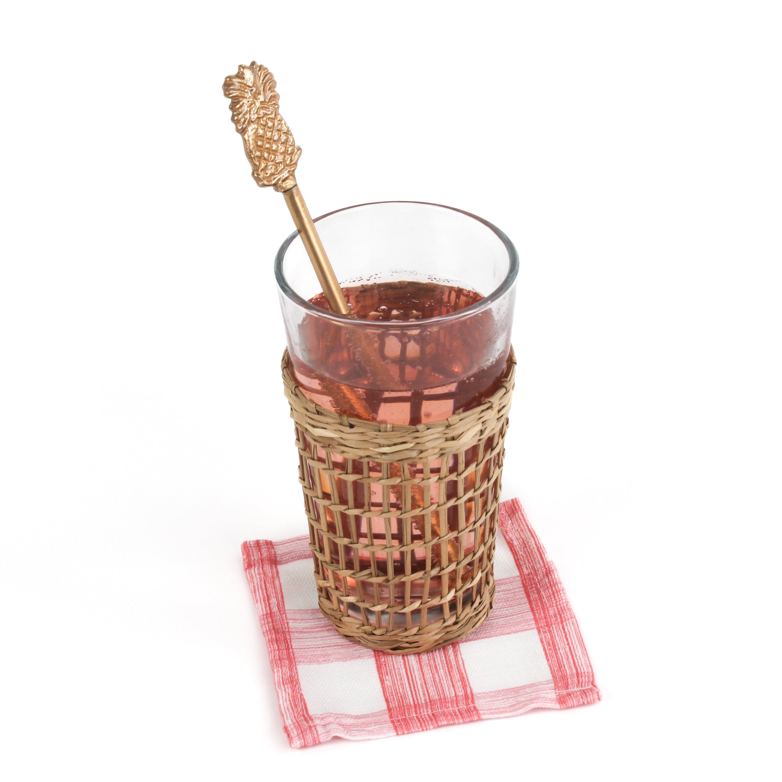 a gold pineapple-shaped drink stirrer on a glass of water on a white background