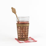 a gilt metal gold christmas swizzle stick with decorative santa ends on a glass of water