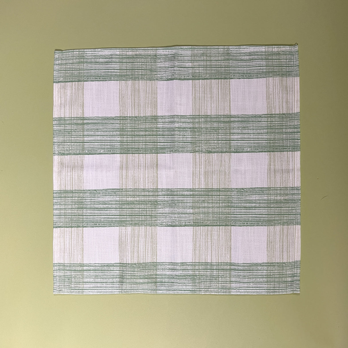 a green  gingham dinner napkins in gin lane print fabric by madap cottage on a light green background. 