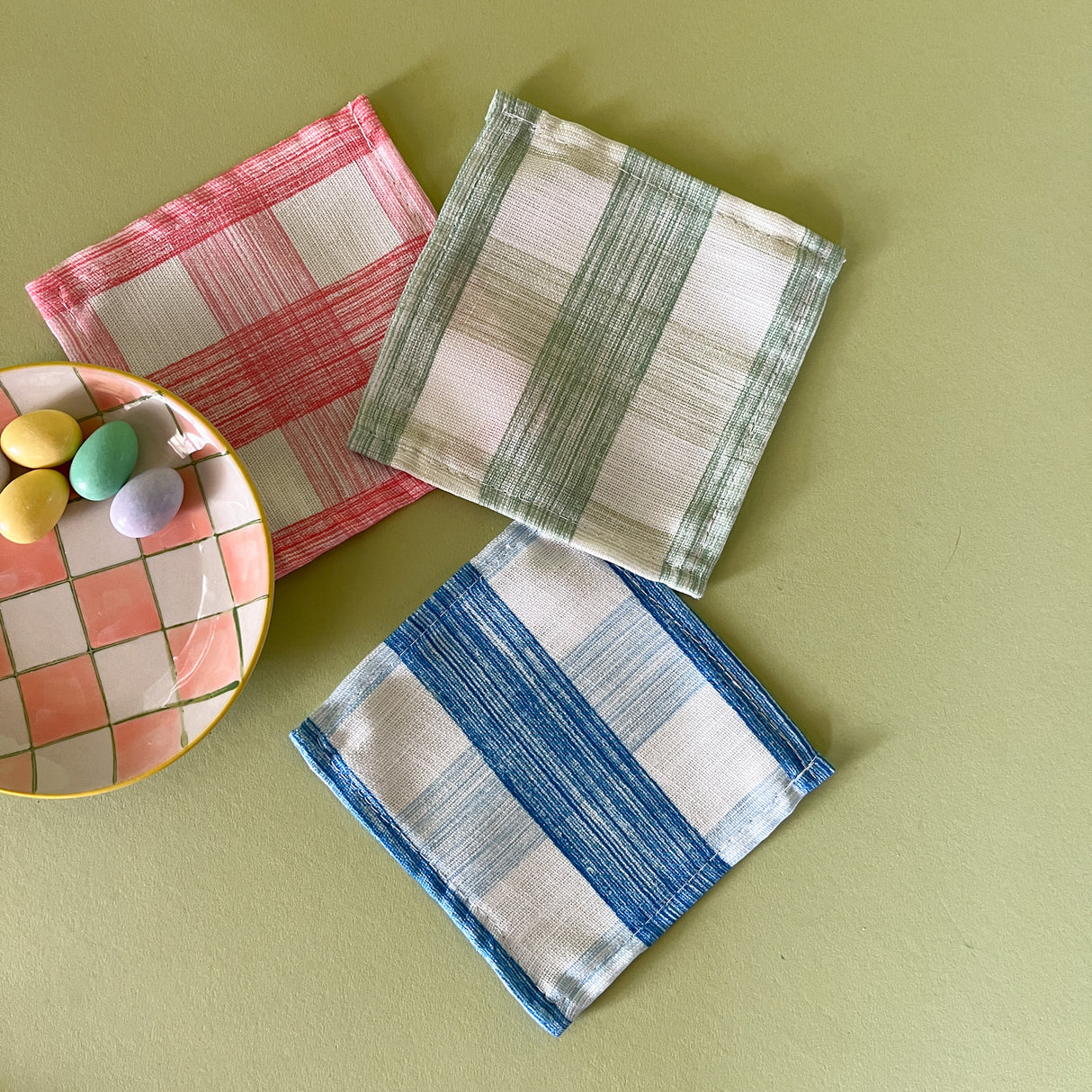 Three gingham cocktail napkins with small plate of easter eggs.