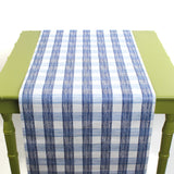 a green table covered by a Gin Lane Blue Gingham Paper Table Runner on a white background