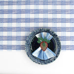 a ceramic plate on top of a Gin Lane Blue Gingham Paper Table Runner on a white background
