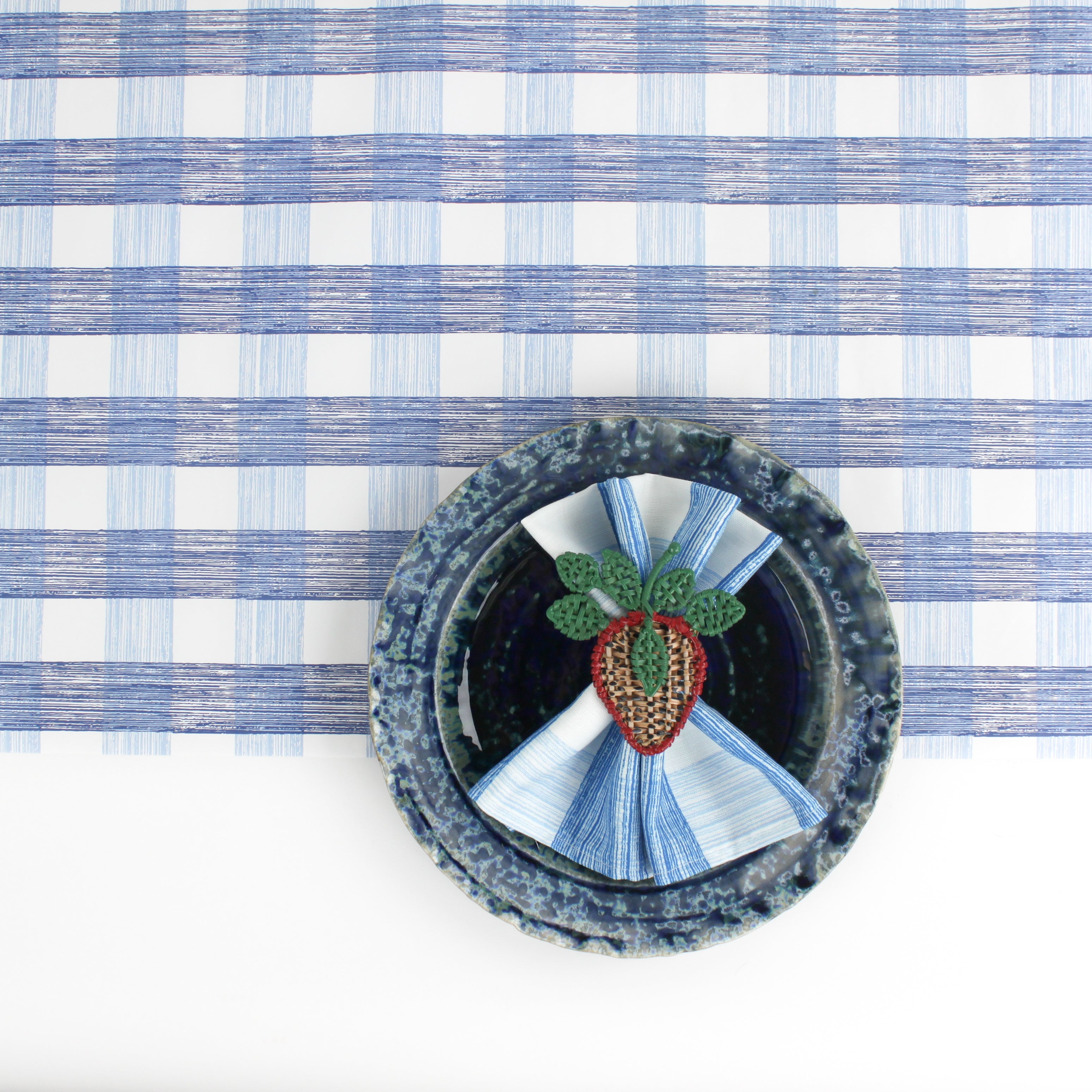 a ceramic plate on top of a Gin Lane Blue Gingham Paper Table Runner on a white background