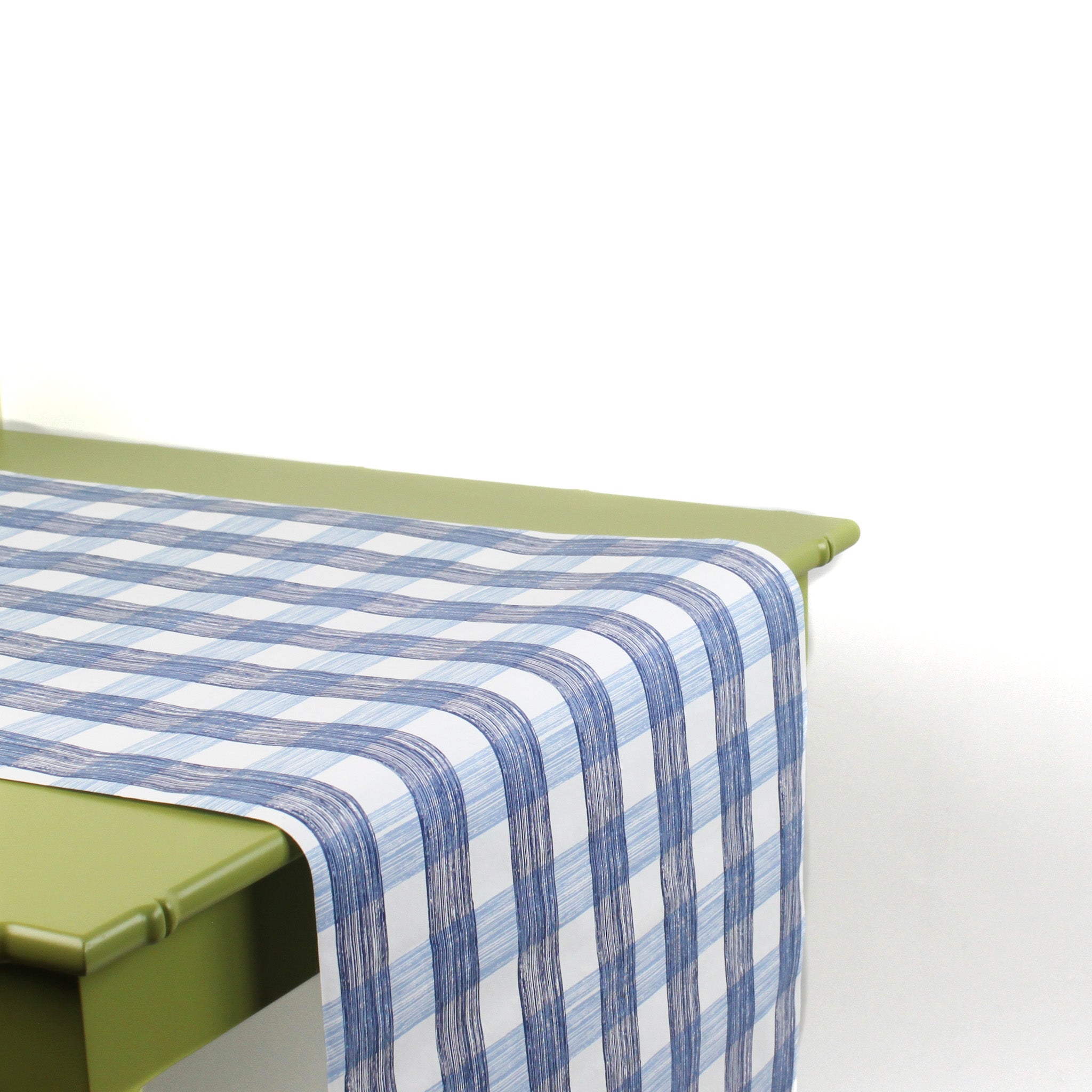 a green table covered by a Gin Lane Blue Gingham Paper Table Runner on a white background