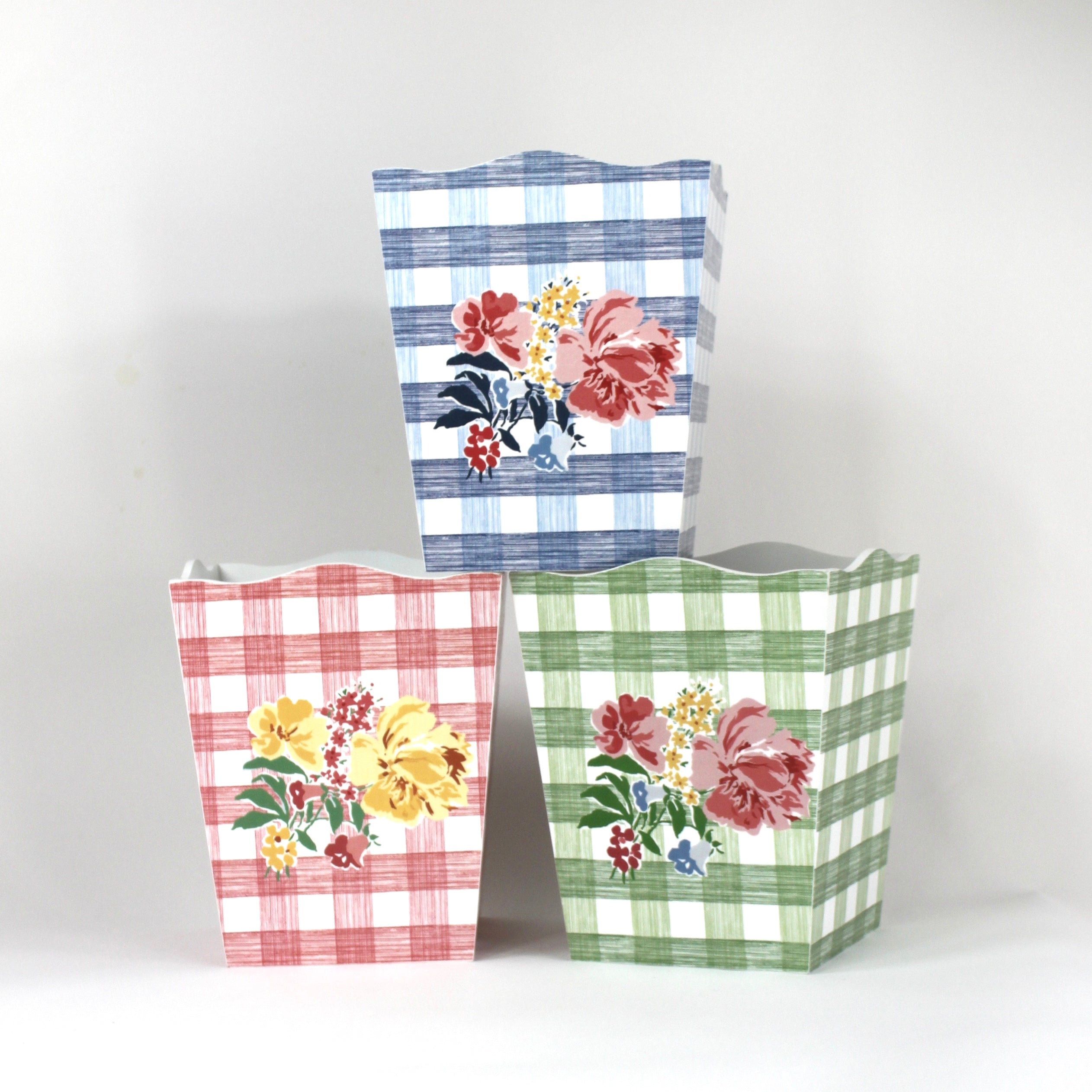 a trio of gingham with floral motif wastepaper baskets - one pink, one blue and one green. 