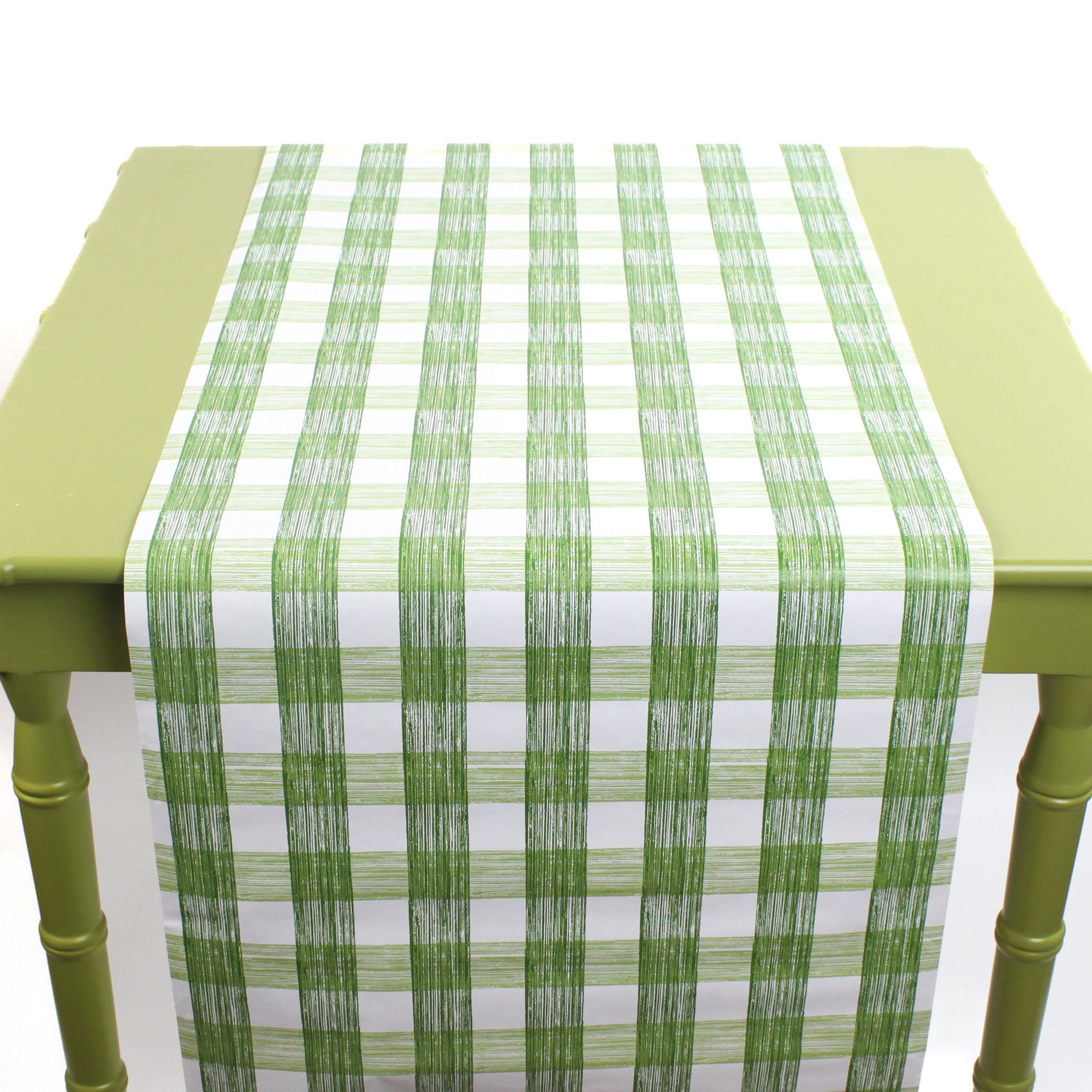 a green table covered by a Gin Lane Green Gingham Paper Table Runner on a white background