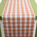 a green table covered with a gingham orange paper table runner in a pattern called gin lane by madcap cottage
