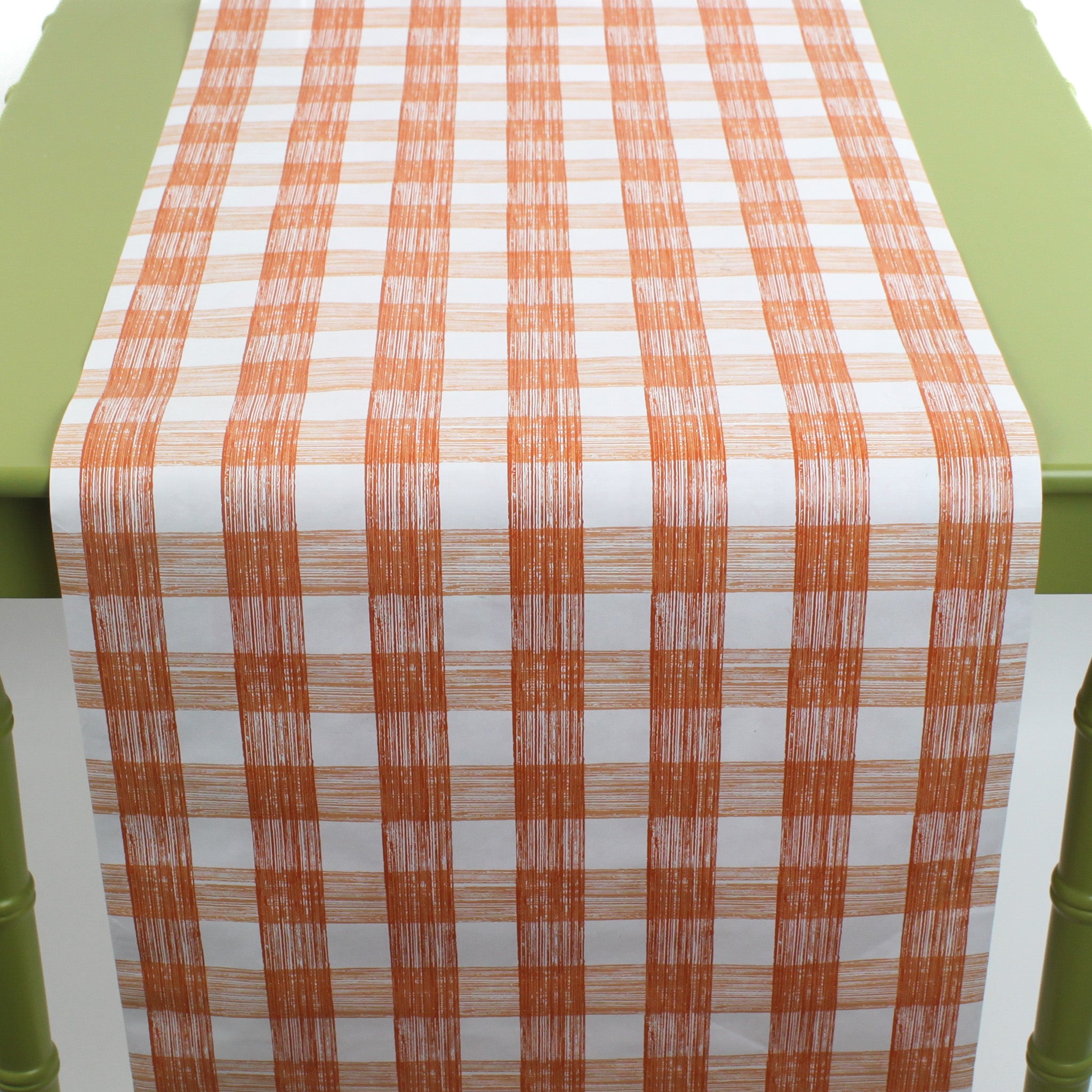 a green table covered with a gingham orange paper table runner in a pattern called gin lane by madcap cottage