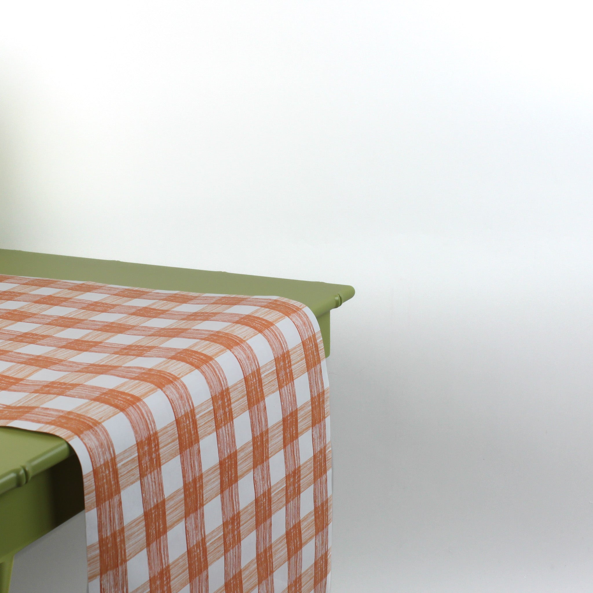 a green table covered with a gingham orange paper table runner in a pattern called gin lane by madcap cottage