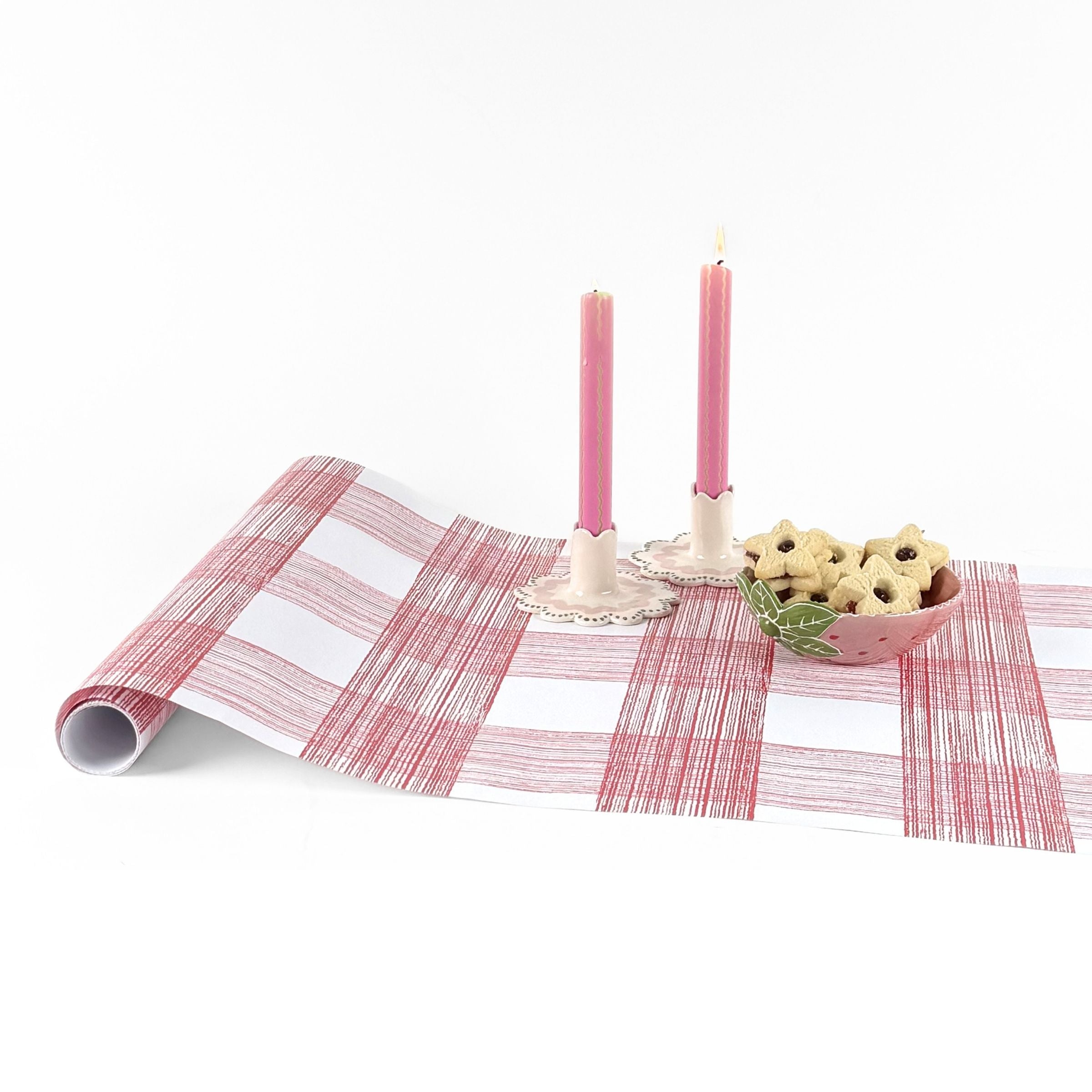 Gingham pink paper table runner styled with pink candles and decorative bowl.