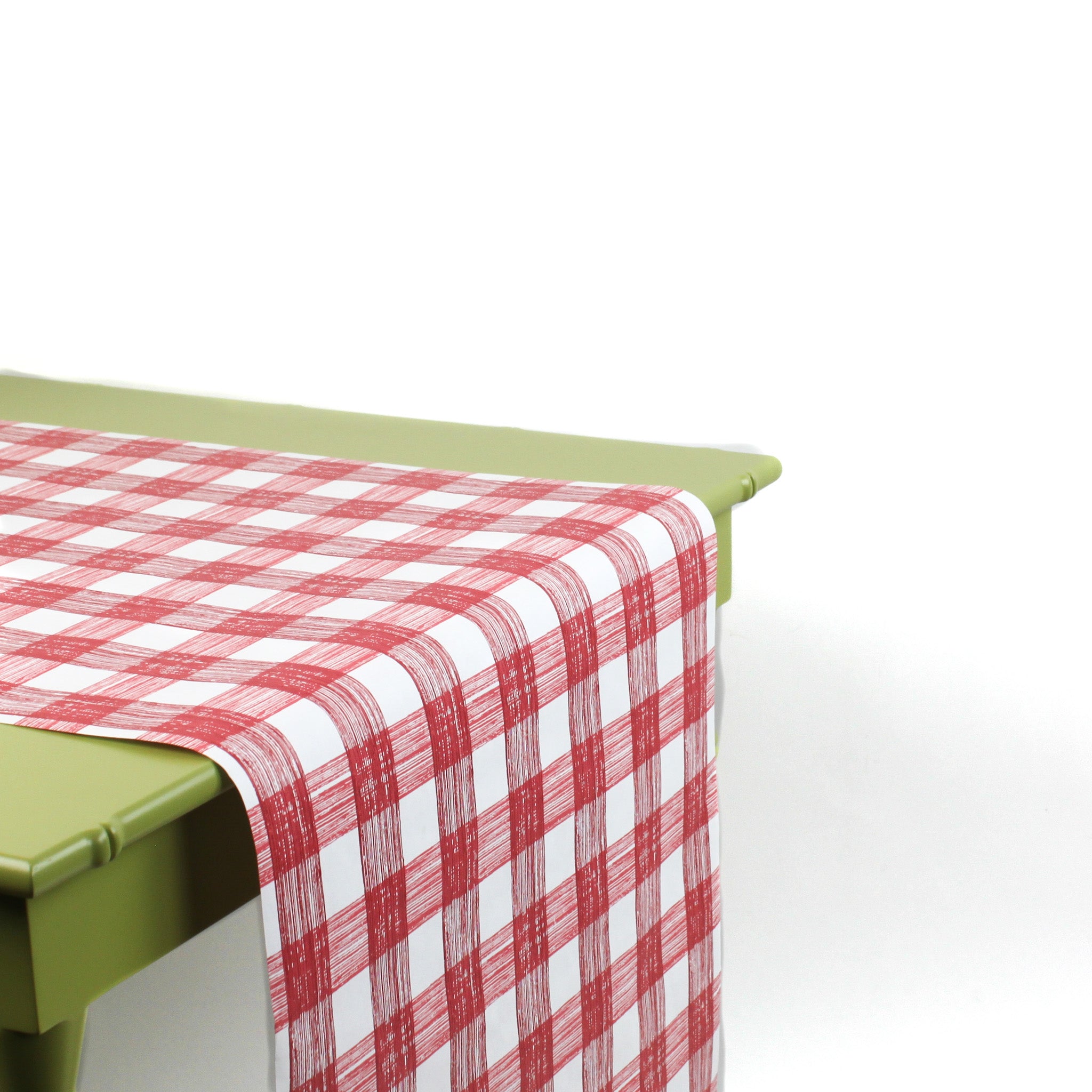 a green table covered by a Gin Lane Red Gingham Paper Table Runner on a white background