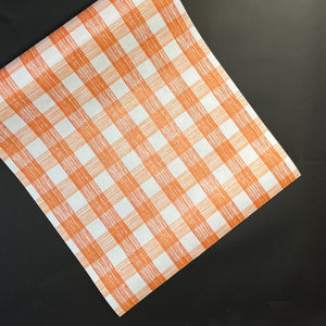 a gingham orange paper table runner in a pattern called gin lane by madcap cottage