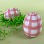 two pink gingham large decorative easter eggs on a green background.