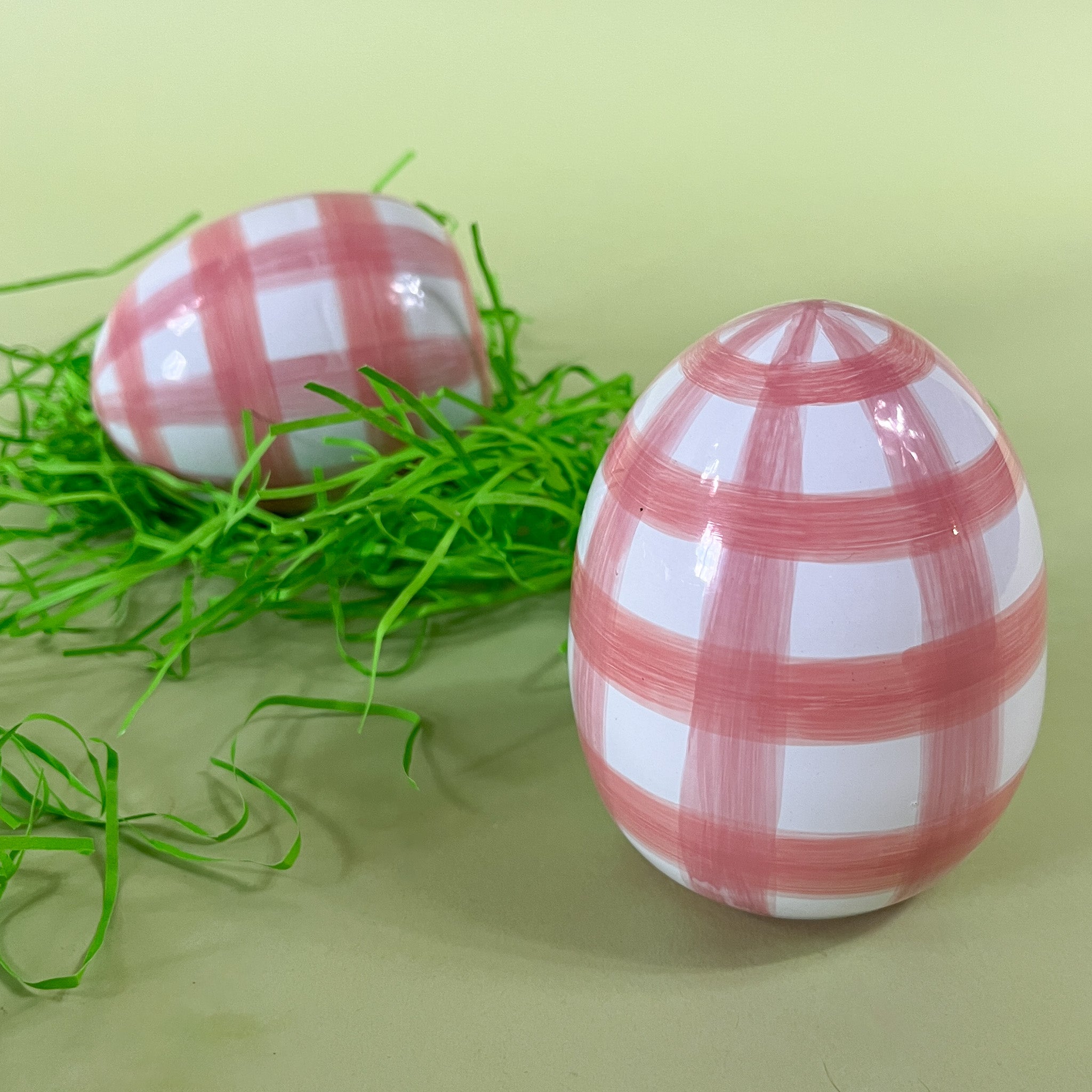 two pink gingham large decorative easter eggs on a green background.