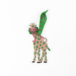Decorative giraffe ornament with green spots and a pink bow on a white background