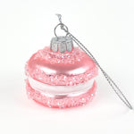 Pink macaron ornament on a silver cord on a white background