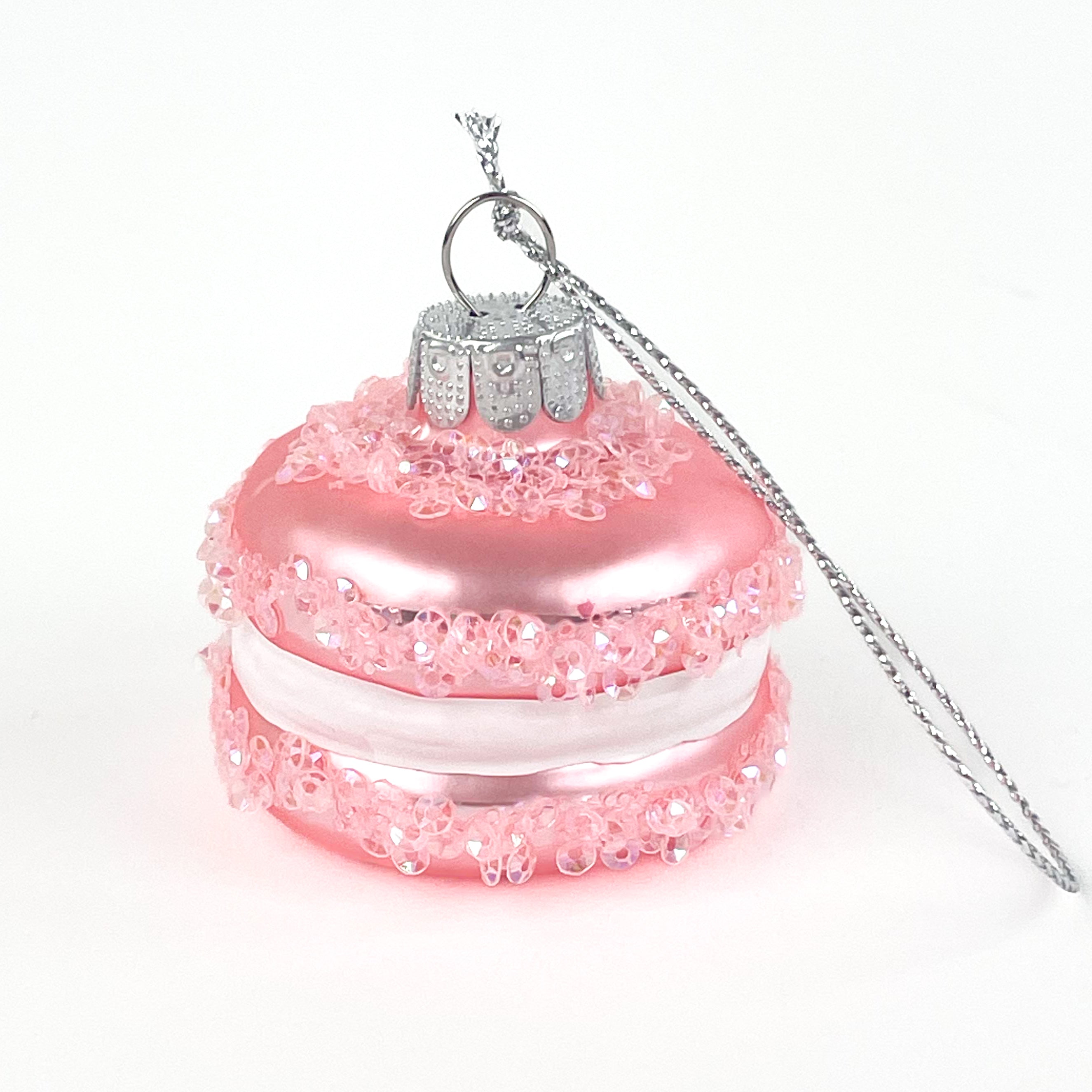 Pink macaron ornament on a silver cord on a white background