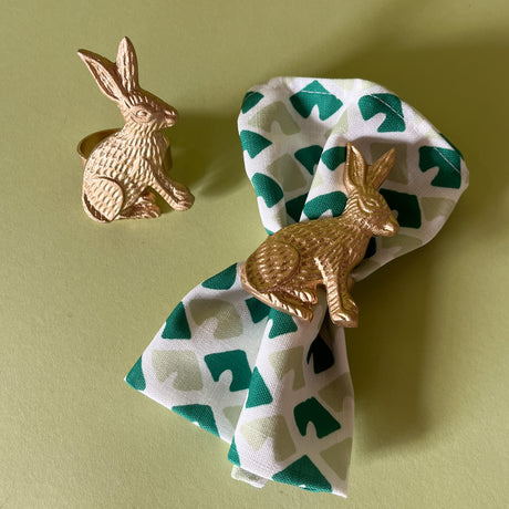 gilt metal bunny napkin ring pair with one on a green dinner napkin