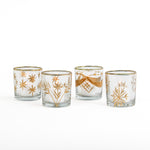 Four glass candle holders with gold floral designs on a white background