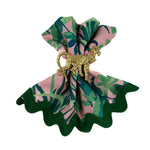 Gold monkey napkin ring displayed on a folded pink and green patterned cloth napkin with scalloped green edges.