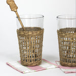 a  gold pineapple swizzle sticks from madcap cottage resting in a seagrass wrapped glass