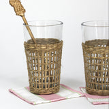 a  gold pineapple swizzle sticks from madcap cottage resting in a seagrass wrapped glass