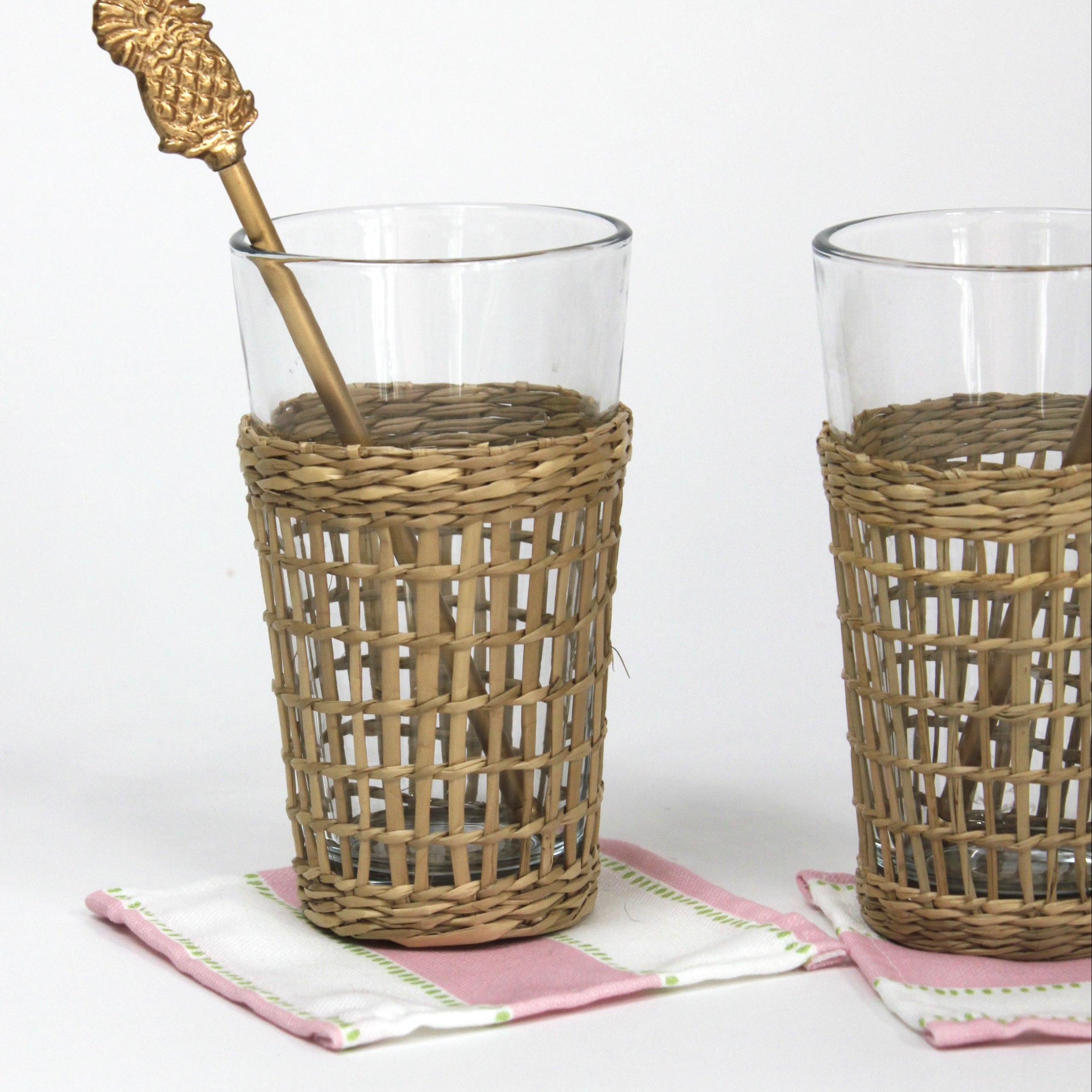 a  gold pineapple swizzle sticks from madcap cottage resting in a seagrass wrapped glass