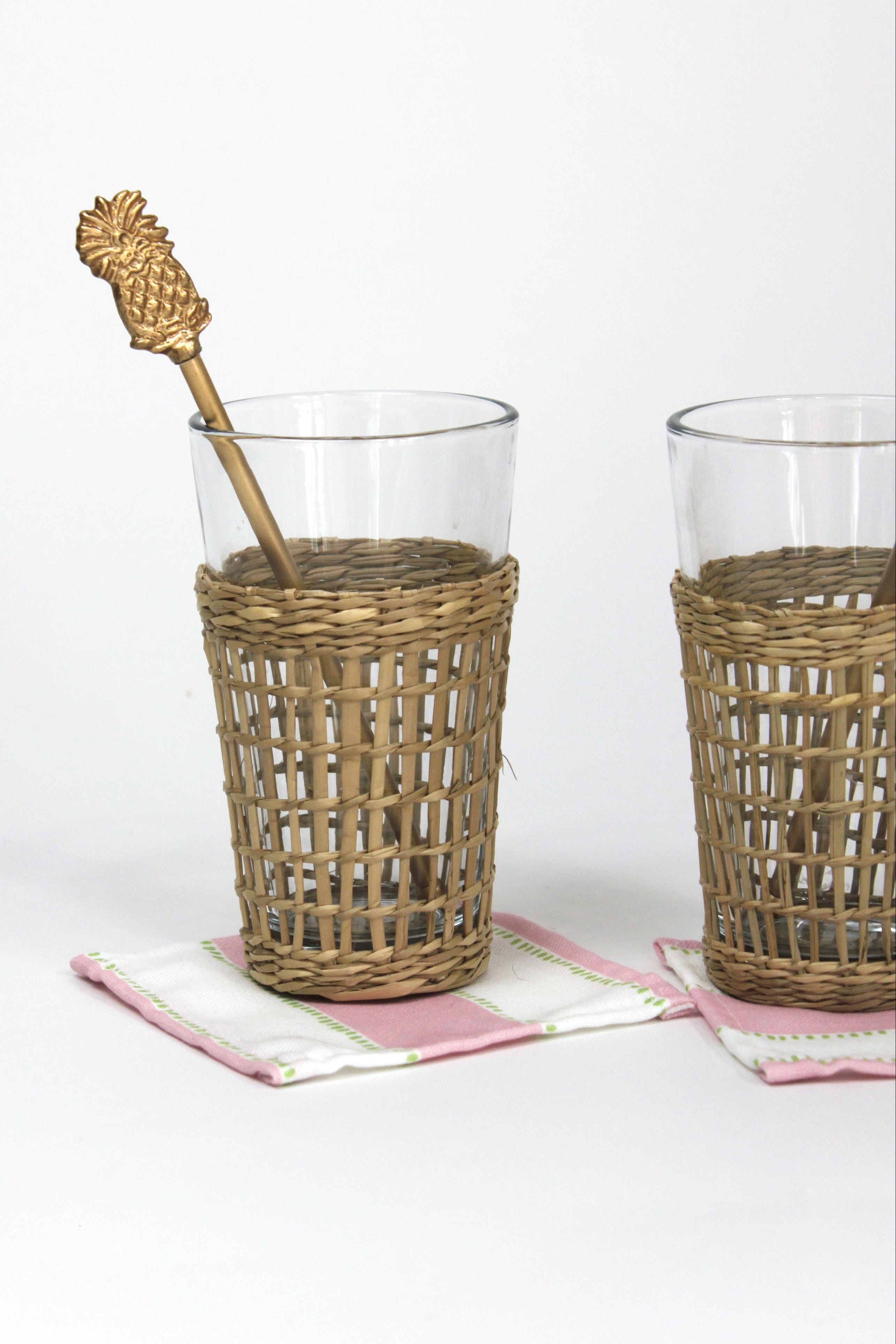 a  gold pineapple swizzle sticks from madcap cottage resting in a seagrass wrapped glass