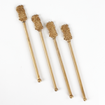Four gold pineapple-shaped drink stirrers on a white background