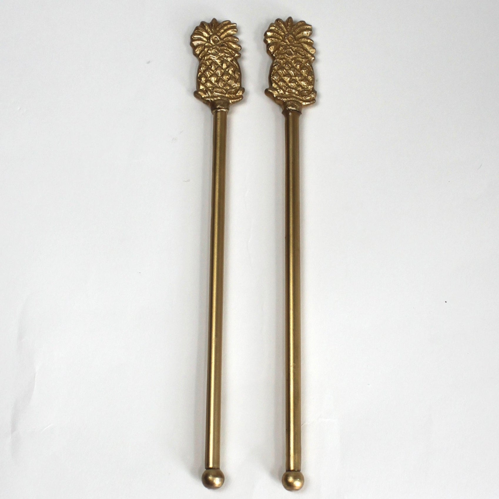 a pair of gold pineapple swizzle sticks from madcap cottage