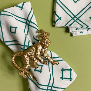 gilt metal monkey napkin ring on a white and green dinner napkin