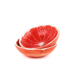 two stacked bowls that look like grapefruits against a white background. 