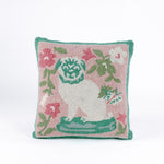 Square decorative pillow with a hooked texture, featuring a white pug with green details surrounded by pink, white, and green floral accents on a blush pink background.