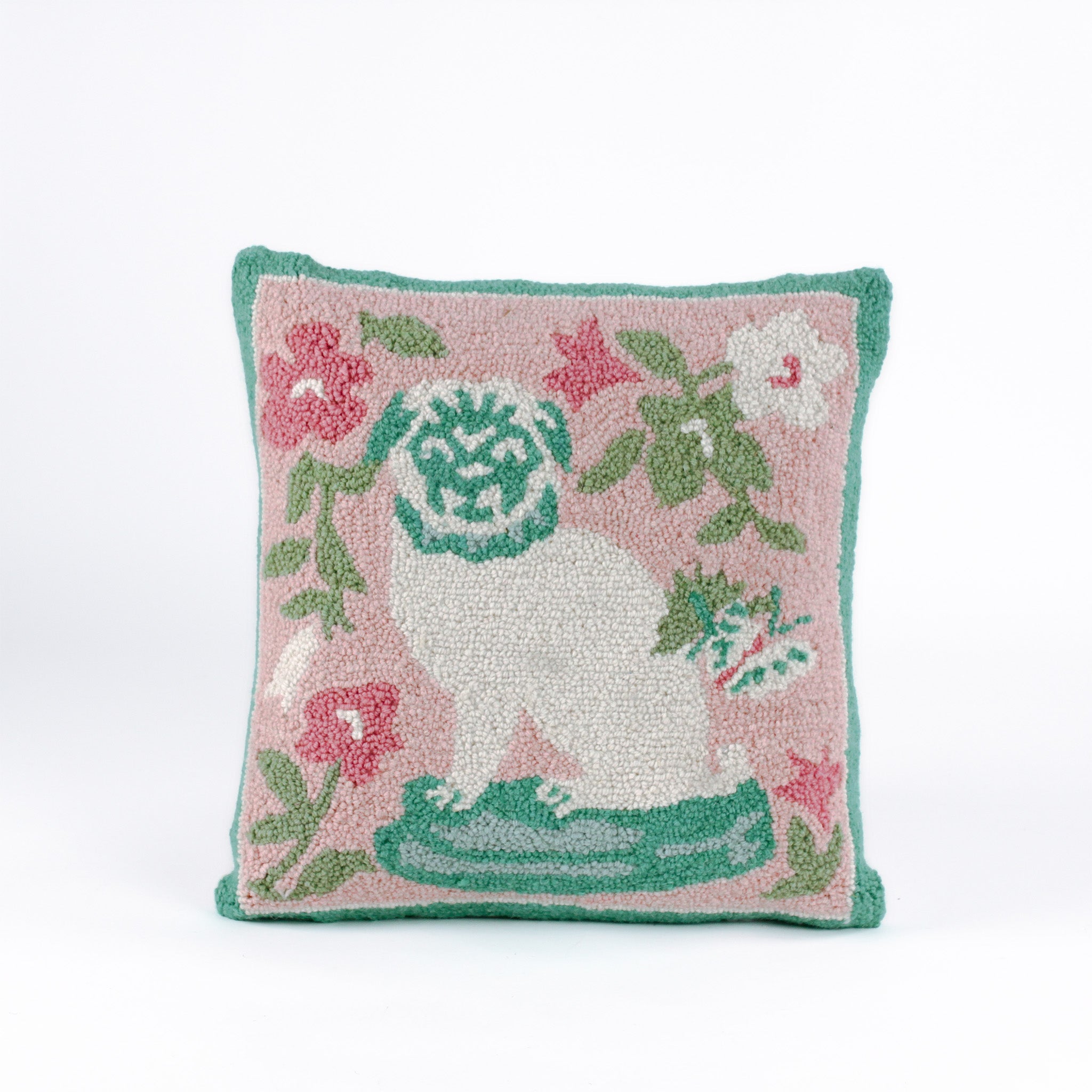 Square decorative pillow with a hooked texture, featuring a white pug with green details surrounded by pink, white, and green floral accents on a blush pink background.