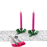 pink taper candles with green bow candle holders on confetti table setting