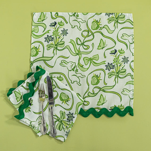 Bunnies and bow print clothnapkins in green with cutlery against a green background.