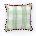 Square decorative pillow with a light green gingham plaid pattern on a white background, finished with a red scalloped trim around the edges.