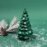 Green marbled ceramic Christmas tree decoration with frosted pine branches and pinecones on a snowy green background