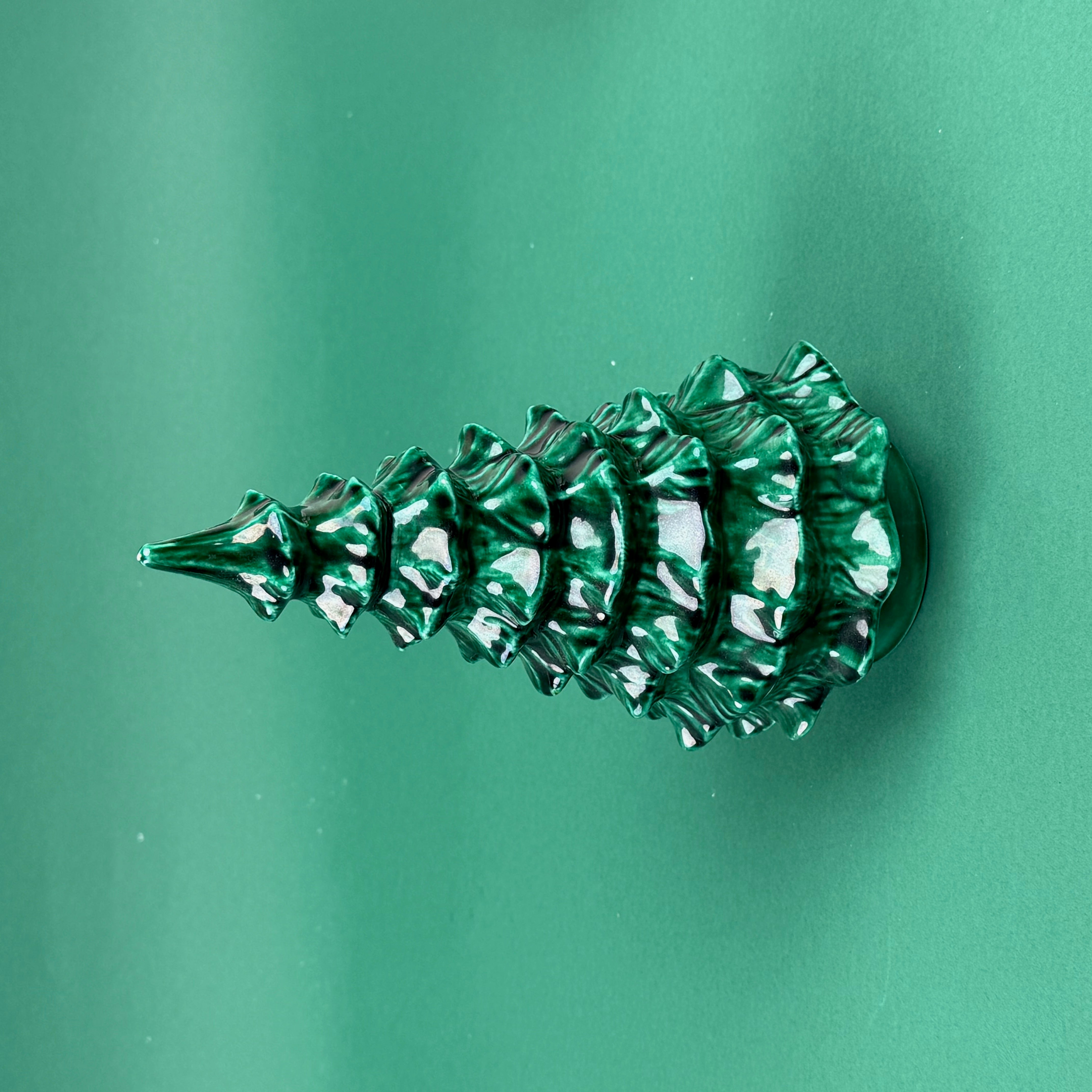Side view Green marbled Christmas tree ornament on a solid green background