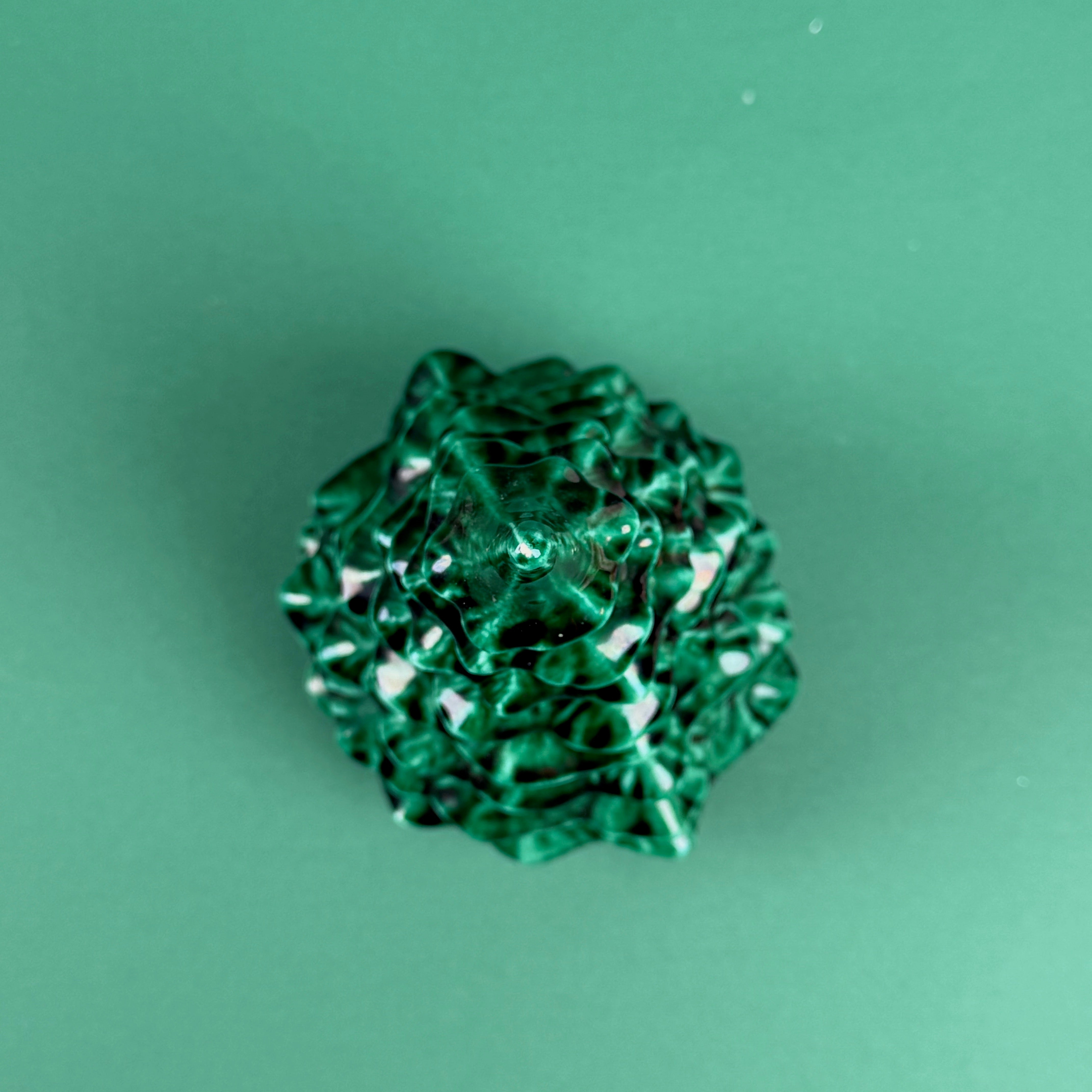 Green marbled Christmas tree ornament on a solid green background