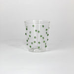 Clear glass with green polka dots on a white background